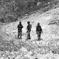 Black-and-white photo of three Israeli soldiers standing near circular barbed-wire fencing